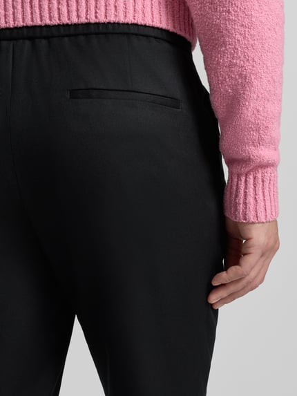 Mężczyznamodel nosi Slim Fit Stoffhose aus Lyocell-Mix Modell 'GETLIN251F3' od HUGO, czarna, splot skośny, detal kieszeni, krój slim fit, lyocell-mix, widok detalu tylnej kieszeni