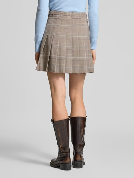 Frauenmodel trägt Minirock mit Viskose-Anteil Modell 'Geraldine' von Guess, A-Linie, Stoffgürtel, Elastischer-Material-Mix, Ganzkörperansicht Rückansicht.