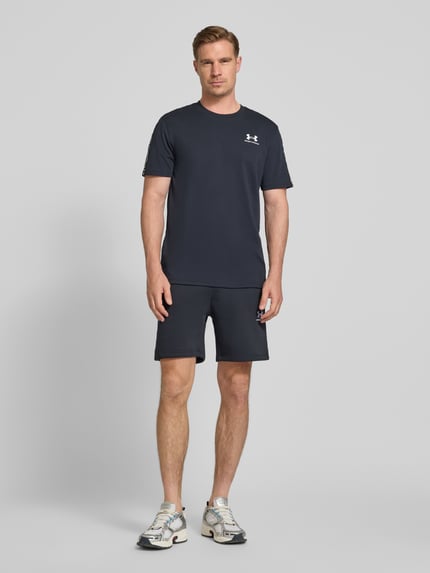 Männermodel trägt Regular Fit T-shirt mit logostitching Modell 'Icon' van Under Armour aus katoenmix, ronde hals, ruglengte maat M 72 cm, ganzlichaamsvoorzijde.