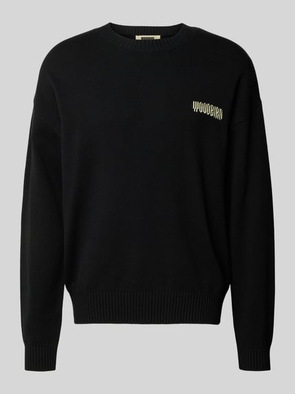 Produktfoto, czarny Strickpullover mit gerippten Abschlüssen Modell 'Kurt' von WOODBIRD z bawełnianej mieszanki, luźny krój, okrągły dekolt, widoczne logo marki.