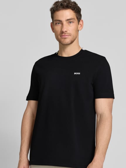 Männermodel trägt Regular Fit T-Shirt aus Baumwoll-Piqué Modell 'TS_PIQUE' von BOSS Green in Schwarz mit Label Stitching, Nahaufnahme Oberkörper.