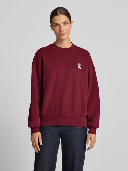 Vrouwenmodel draagt bordeauxrood oversized sweatshirt uit pure katoen model 'ALIZAA' van ARMEDANGELS, Dames sweatshirt, full body voorkant.