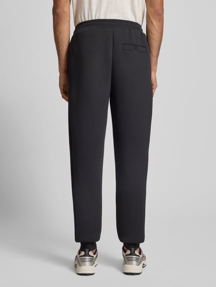 Männermodel draagt zwarte Sweatpants met logo model 'SIRTORI' van Ellesse, regular fit, elastische tailleband, Ganzkörperansicht Rückansicht.