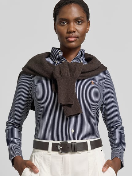 Frauenmodel trägt Slim Fit Hemdbluse aus reiner Baumwolle von Polo Ralph Lauren mit dunkelblauen und weißen Streifen, Nahaufnahme Oberkörper.