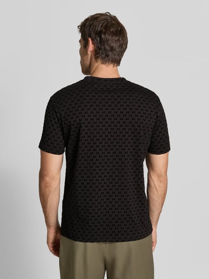 Männermodel trägt Regular Fit T-Shirt mit Allover-Print von Armani Exchange in Schwarz, kurzärmelig, Rückansicht, Ganzkörperansicht Rückansicht.
