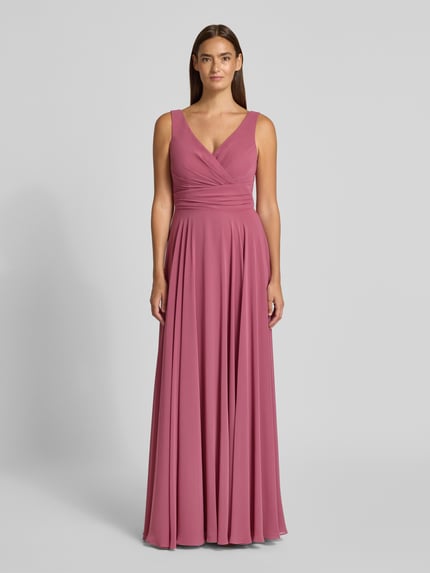 Frauenmodel trägt Abendkleid mit V-Ausschnitt von TROYDEN COLLECTION in Rosé, A-Linie, Maxikleid, Reißverschluss, Ganzkörperansicht von vorne. Rückenlänge bei Größe 36: 155 cm, Brustweite bei Größe 36: 43 cm.