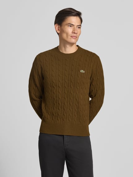 Männermodel trägt Regular Fit Pullover aus reiner Wolle von Lacoste in Braun mit Strukturmuster, Nahaufnahme Oberkörper, Herren Pullover von Lacoste.