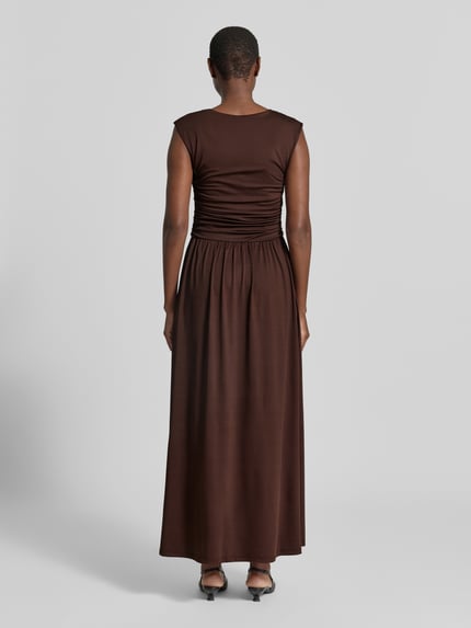 Frauenmodel trägt Maxikleid mit Kappärmeln Modell 'WINJA' von YAS, taillierter Schnitt, brauner Stoff, Rückenansicht, Ganzkörperansicht Rückansicht.