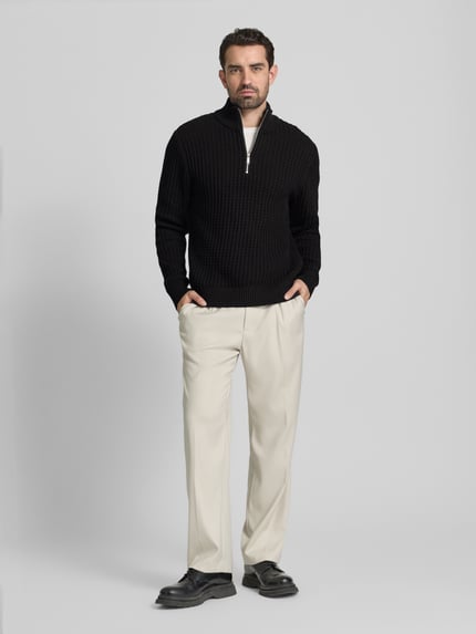 Männermodel draagt Regular Fit Troyer in Waffel-Struktur Modell 'TOM' van SELECTED HOMME, zwart, gebreid uit biologische katoen, unicolor, lange mouwen, geribde boorden, korte rits, label patch, volledig lichaam vooraanzicht.