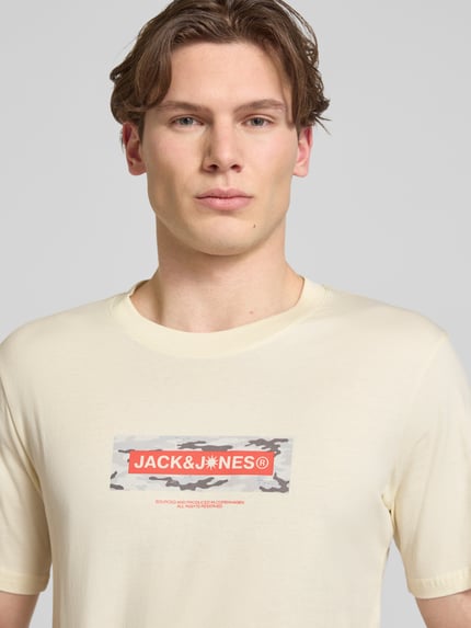 Männermodel trägt T-Shirt mit Logo und Rundhalsausschnitt von Jack & Jones in Beige, reine Baumwolle, Regular Fit, Nahaufnahme Oberkörper.