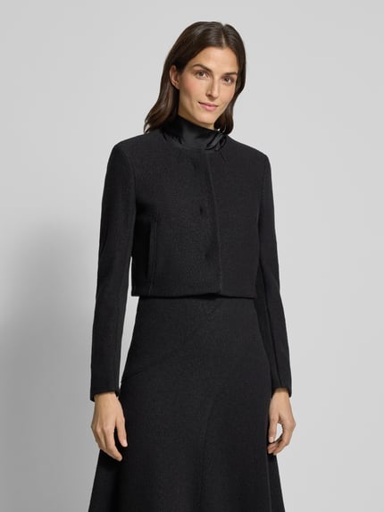 Modelka kobieca nosi Boxy Fit Kurzblazer aus reiner Schurwolle Modell 'JICENA' od BOSS, czarny, gładki, długi rękaw, widok całej sylwetki z przodu.