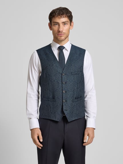 Männermodel trägt Regular Fit Weste mit Schurwoll-Anteil Modell 'Waldo' von Carl Gross, floraler Allover-Print, Paspeltaschen, V-Ausschnitt, Knopfleiste, Elastischer-Material-Mix, Farben in Blau und Weiß, strukturierte Oberfläche, Ganzkörperansicht von vorne.