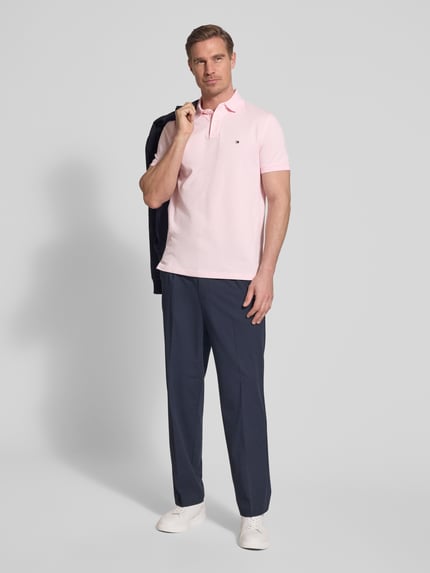 Männermodel trägt Regular Fit Poloshirt aus Baumwoll-Mix von Tommy Hilfiger, Optik:Unifarben, Logo-Stitching, Piqué, Ganzkörperansicht von vorne.
