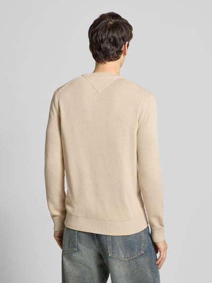 Männermodel trägt Regular Fit Strickpullover aus reiner Baumwolle van Tommy Jeans, unikleurig, logo detail, ribboorden, Ganzkörperansicht Rückansicht.