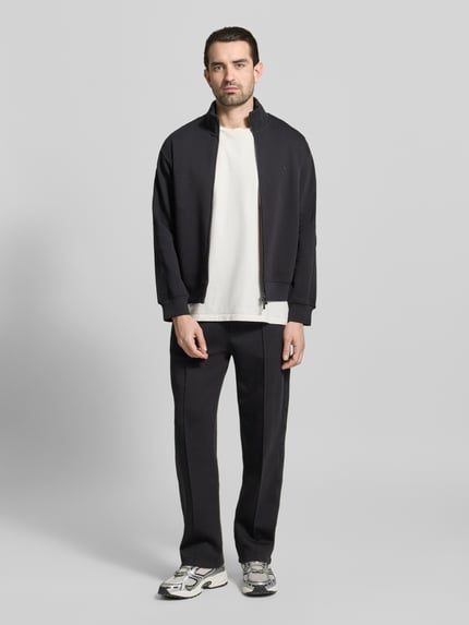 Männermodel trägt Sweatjacke mit Stehkragen und Zweiwege-Reißverschluss von Emporio Armani, Baumwoll-Mix mit Stretch-Anteil, Regular-Fit, Schwarz, Eingrifftaschen, Ganzkörperansicht von vorne.
