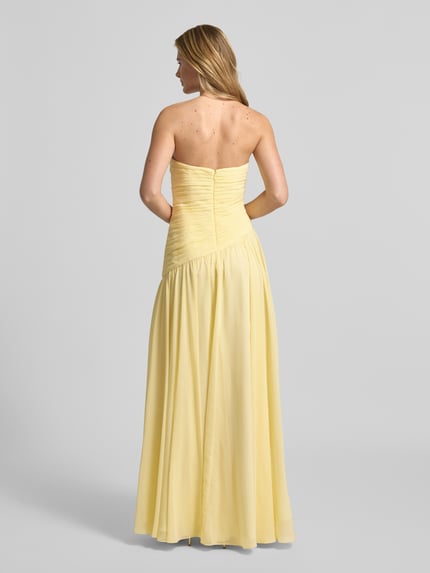 Frauenmodel trägt Slim Fit Abendkleid in Falten-Optik von Luxuar, gelber Stoff, schulterfrei, blickdichter Unterrock, Ganzkörperansicht Rückansicht.