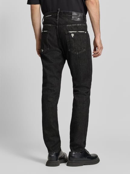 Męski model nosi czarne jeansy Straight Fit Jeans aus Baumwoll-Mix Modell 'Teddy' von Dsquared2, Przetarcia, 5 kieszeni, zapięcie na guzik i zamek błyskawiczny, Mieszanka bawełny i elastanu, Szerokość w rozmiarze 50: 46 cm, długość wewnętrzna nogawki w rozmiarze 50: 83 cm, widok całej sylwetki z tyłu.