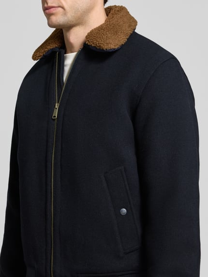 Männermodel trägt Regular Fit Jacke mit Umlegekragen und Reißverschluss van JACK & JONES premium, materiaalmix met wol, donkerblauw met bruine platte kraag, ritssluiting, zak met knoop, context: ruglengte maat M 65 cm, schouderbreedte 49 cm, borstwijdte 60 cm, mouwlengte 66 cm, detailaufnahme, heren jack.