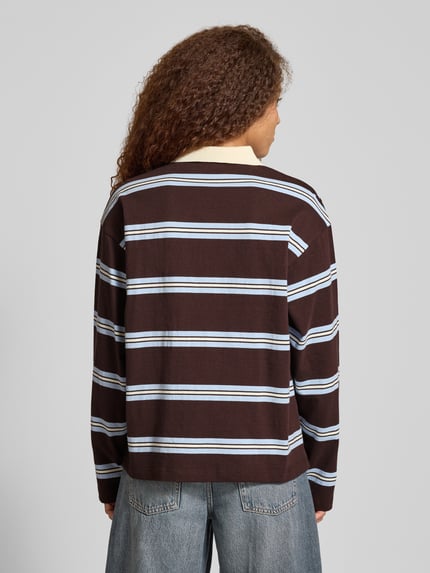 Frauenmodel trägt Relaxed Fit Poloshirt mit Label-Detail Modell 'Jolina' von OH APRIL, braun mit weißen und blauen Streifen, Longsleeve, reine Baumwolle, Rückenlänge bei Größe S 64 cm, Ganzkörperansicht Rückansicht.