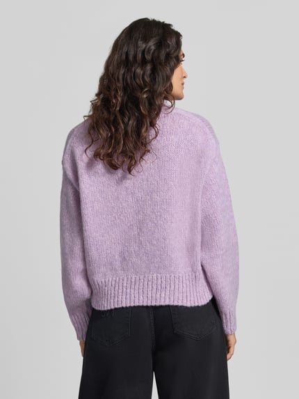 Modelka nosi sweter wełniany 'Pullover aus Wolle Alpaka mit Rippbündchen' od MARC CAIN, krój regular fit, efekt: jednolity kolor, imitacja dzianiny, długość: krój krótki, długie rękawy z obniżoną linią ramion, okrągły dekolt, prążkowane wykończenia; widok całej sylwetki z tyłu.