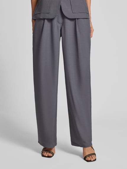 Frauenmodel trägt Wide Fit Stoffhose mit Bundfalten Modell 'Harper' von Samsøe Samsøe, elastischer Material-Mix, Ganzkörperansicht von vorne.
