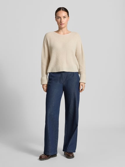 Frauenmodel trägt Strickpullover aus Alpaka-Mix Modell 'MENY' von DRYKORN, locker geschnitten, beige Farbe, weiche Textur, Ganzkörperansicht von vorne.