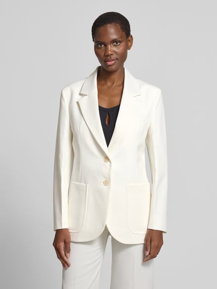 Kobiece modelka nosi Blazer aus Woll-Mix mit Brusttasche od Victoria Beckham, kolor kremowy, krój taliowany, kieszeń na piersi, naszywane kieszenie, zapięcie na dwa guziki, długość tyłu w rozmiarze 36: 73 cm, szerokość w rozmiarze 36: 46 cm, długość rękawa w rozmiarze 36: 63 cm, struktura delikatnie fakturowana, szerokie klapy, gładkie wykończenie, widoczne guziki, Ganzkörperansicht von vorne.