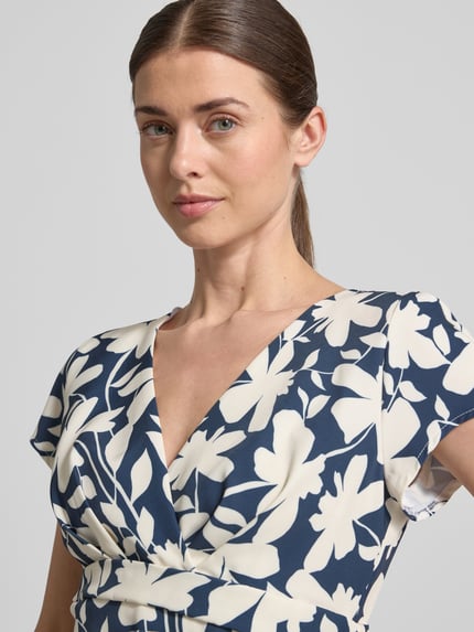Vrouwenmodel draagt cocktailjurk met V-hals en tailleband van Swing in materiaalmix met stretch, all-over look, nahaufnahme bovenlichaam.