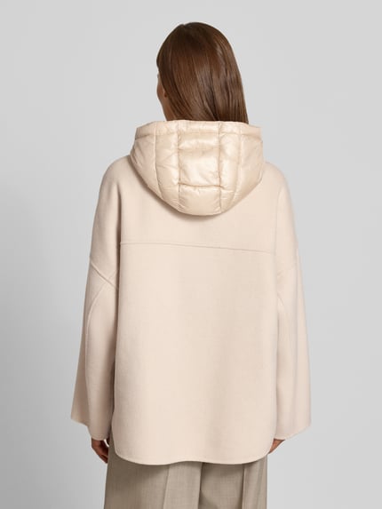Frauenmodel trägt Jacke mit Kapuze von COMMA in Beige, lockere Passform, gesteppte Kapuze, Rückenansicht, Nahaufnahme Oberkörper.