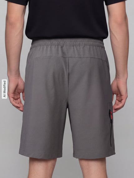 Männermodel trägt Regular Fit Sportshorts mit Label-Print von PUMA Performance in Grau, lockerer Schnitt, glatte Textur, Ganzkörperansicht Rückansicht.