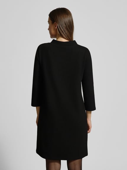 Vrouwenmodel draagt Mini-jurk met 3/4-mouwen van More & More in zwart, katoenmix, getailleerd model, steekzakken, ruglengte 88 cm, Ganzkörperansicht Rückansicht.