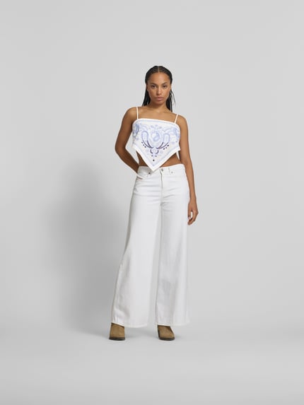Kobiece modelka nosi Crop Bandeau-Top aus Leinen-Mix od Self-Portrait, mieszanka lnu i bawełny, krój regular fit, hafty paisley, cienkie ramiączka, kokarda wiązana z tyłu, długość tyłu w rozmiarze S: 36 cm, widok całej sylwetki z przodu.