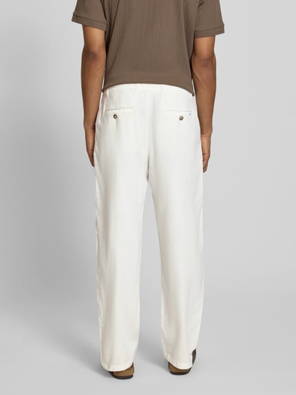 Männermodel trägt Loose Fit Hose aus Baumwoll-Leinen-Mix Modell 'BRODY' von SELECTED HOMME in creme, Struktur-Flammgarn, Ganzkörperansicht Rückansicht.