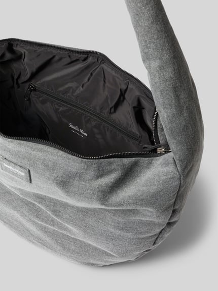 Produktfoto, Shoulder Bag aus reiner Baumwolle in Denim-Optik von Studio Noos, Główna przegroda z zamkiem błyskawicznym, pasek na ramię, detal z logo, przegródka wewnętrzna zapinana na zamek błyskawiczny, Szerokość w rozmiarze 1: 49 cm, Długość w rozmiarze 1: 35 cm, Głębokość w rozmiarze 1: 11 cm, długość paska na ramię w rozmiarze 1: 80 cm, tkanina stylizowana na denim.
