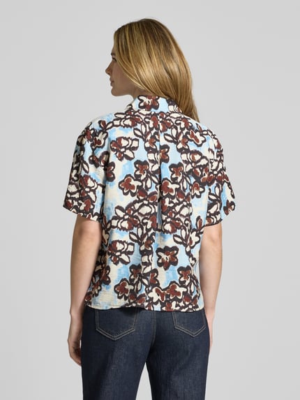 Frauenmodel trägt Regular Fit Bluse im Allover-Look von JAKE*S STUDIO WOMAN aus Viskose-Mix mit Hemdblusenkragen, Knopfleiste und 1/2-Arm, Rückenlänge bei Größe 36: 60 cm, Ärmellänge 21 cm, Muster in Braun und Blau, Struktur leicht texturiert, Ganzkörperansicht Rückansicht.