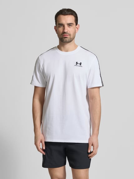 Männermodel trägt weißes Regular Fit T-Shirt mit Logo-Stitching Modell 'Icon' von Under Armour, Baumwoll-Mix, Ganzkörperansicht von vorne.
