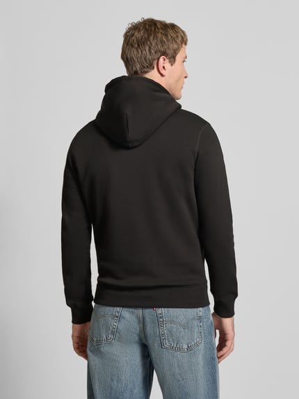 Männermodel trägt Hoodie mit Känguru-Tasche von REVIEW aus schwarzer Baumwollmischung, Slim-Fit, elastische Abschlüsse, Ganzkörperansicht Rückansicht.