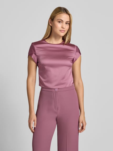 Frauenmodel trägt Bluse aus Satin von Rinascimento in glänzendem Violett, kurzärmelig, Rundhalsausschnitt, Nahaufnahme Oberkörper.