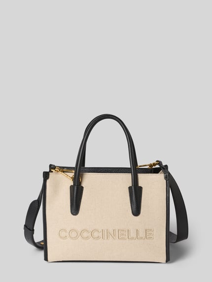 Produktfoto, Handtasche mit Label-Stitching von Coccinelle aus beigefarbenem Stoff mit schwarzen Details, Tragehenkel, Schulterriemen, Hauptfach mit Reißverschluss, Maße: Breite 27 cm, Länge 20 cm, Tiefe 13 cm, Länge Schulterriemen 105 cm