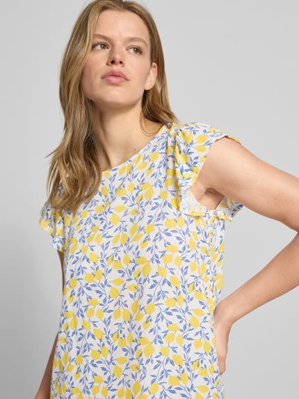 Frauenmodel trägt Regular Fit Sommerkleid aus reiner Viskose Modell 'BARRI' von Pieces, Optik:Allover-Muster in Gelb und Blau, Kurzarm, Schmetterlingsärmel, Crêpe-Material, Rundhals-Ausschnitt, Knopf mit Öse, Nahaufnahme Oberkörper.