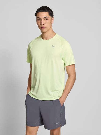 Männermodel trägt T-Shirt mit Logo und Rundhalsausschnitt von PUMA PERFORMANCE in Hellgrün, Regular Fit, glatte Textur, Nahaufnahme Oberkörper.