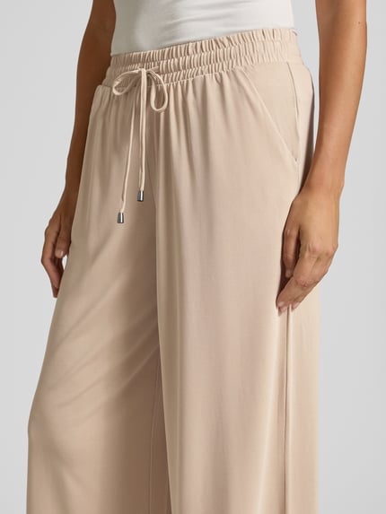 Vrouwenmodel draagt Straight Fit Stoffhose in verkürzter Passform van Christian Berg Woman, modalmix, elastische band met tunnelkoord, beige, detailopname taille.