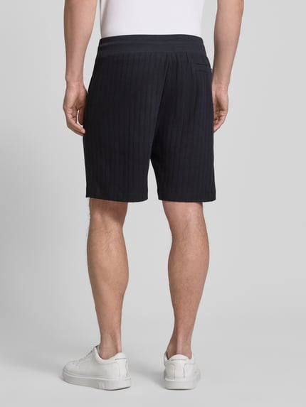 Mężczyzna nosi Regular Fit Shorts mit Tunnelzug Modell 'JUANITO' od JOOP! Collection, kolor ciemnogranatowy, bawełna, szerokość w rozmiarze M: 43 cm, długość nogawki wewnętrznej: 17 cm, widok całej sylwetki z tyłu.
