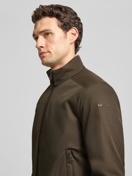 Männermodel trägt Blouson mit Zweiwege-Reißverschluss und Eingrifftaschen von Geox in Oliv, glattes Material, Nahaufnahme Oberkörper, Regular Fit, Stehkragen, KI-modifiziertes Bild.