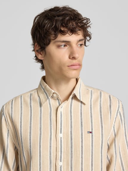 Männermodel trägt Regular Fit Freizeithemd aus Leinen-Baumwoll-Mix von Tommy Jeans, Mehrfarbig, Kentkragen, Gestreift, Nahaufnahme Oberkörper.