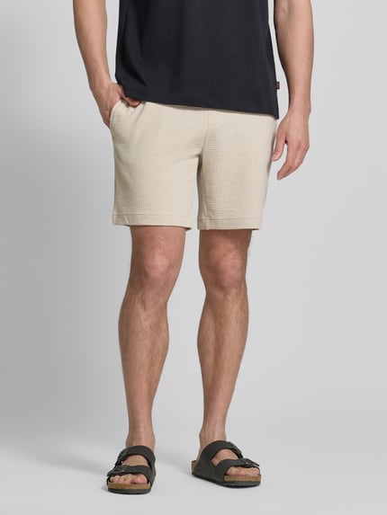 Mężczyzna nosi Regular Fit Sweatshorts aus Baumwoll-Mix Modell 'AUSTIN' od HUGO, beżowy, w fakturę wafla, kieszenie boczne, bawełniany miks, widok całej sylwetki z przodu.
