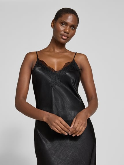 Frauenmodel trägt Maxikleid mit Spitzenbesatz von VERO MODA in Schwarz, glänzender Satin, V-Ausschnitt, Spaghettiträger, Nahaufnahme Oberkörper.