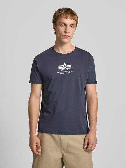 Männermodel trägt T-Shirt mit Logo und Rundhalsausschnitt von Alpha Industries in Dunkelblau, Reine Baumwolle, Regular-Fit, Ganzkörperansicht von vorne.