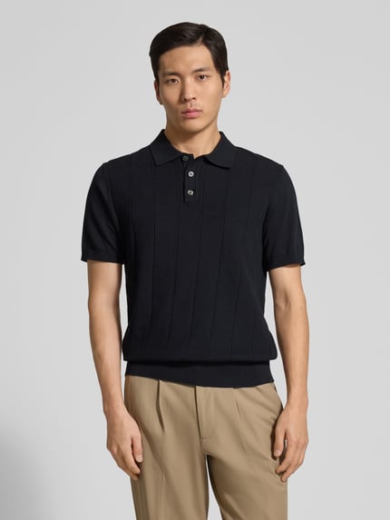 Mannenmodel draagt Regular Fit Poloshirt uit katoen model 'Pima Primo' van Profuomo, zwart met fijne ribstructuur, polokraag, geribde boorden, hele lichaam vooraanzicht.