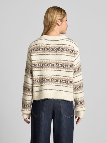 Frauenmodel trägt Pullover mit gerippten Abschlüssen von VERO MODA, mehrfarbiges Allover-Muster in Strickoptik, Ganzkörperansicht Rückansicht.